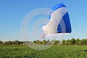 pilot newcomer paraglider is trained on the ground to lift up and hold the blue-white paraplane.