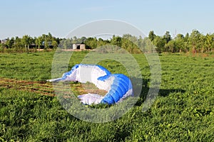 pilot newcomer paraglider is trained on the ground to lift up and hold the blue-white paraplane.