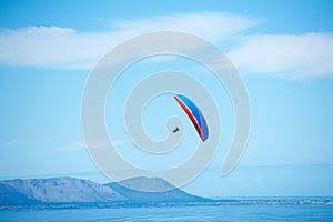 Pilot, parachute and paragliding in blue sky for flight, freedom and courage with extreme sport. Athlete, glide and