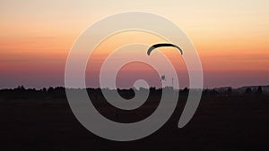 The pilot on a paraglider flies in the sky after sunset with orange . background