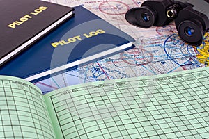 The pilot\'s flight log books on the table with maps, one is open and blank