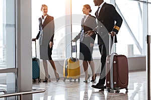 pilot and stewardesses with luggage walking