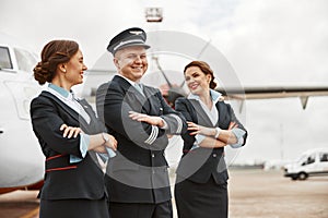 Pilot and stewardesses on runway near airplane jet