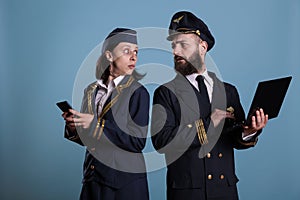 Pilot using laptop, flight attendant messaging on smartphone