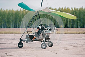 Pilot is using a smart phone and smiling while doing selfie in moto hang-glider