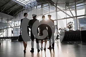 Pilots and stewardesses standing in the airport in front of the panoramic window