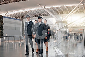 Pilots and stewardesses in uniform walking through the airport terminal