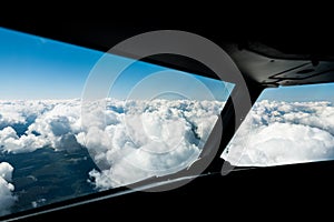 Pilots view out of the cockpit window toward clouds and blue sky above