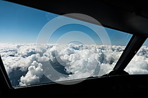 Pilots view out of the cockpit window toward clouds and blue sky above