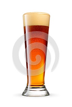 Pilsner glass of fresh dark brown beer with cap of foam isolated on white background