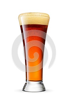 Pilsner glass of fresh dark brown beer with cap of foam isolated on white background