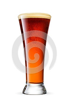 Pilsner glass of fresh dark brown beer with cap of foam isolated on white background