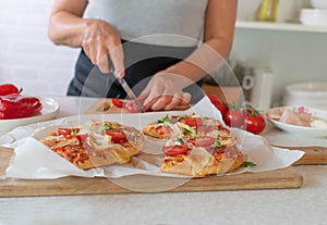 Pimped up baked frozen pizza is prepared by a woman in the kitchen