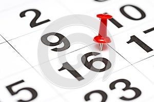 Pin on the date number 16. Sixteen day of month is marked with red thumbtack on calendar. Save the Date concept