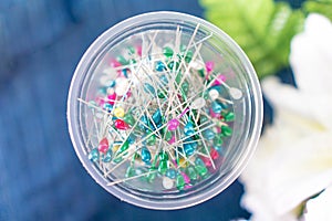 Pin in a plastic cup on a table with a blue cloth.