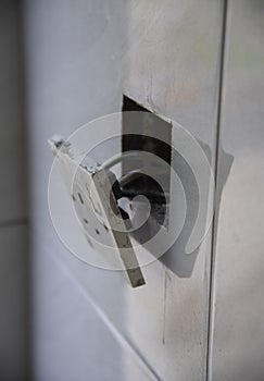 3-pin plug socket adapter hanging out from the wall