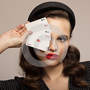 Pin-up girl holding a four aces. Retro fashion portrait