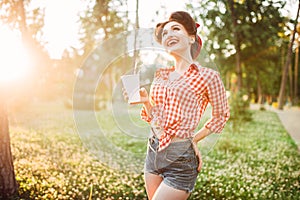 Pin up girl holds cardboard cup with a straw