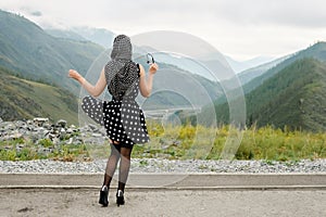 Pin up pose of a young woman on a background of mountains.