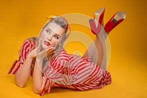 Pin-up stiyle girl lying on a yellow background. Classic soft focus