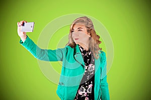 Pin-up woman portrait with bright colors and beautiful make-up holding a smartphone and taking a selfie
