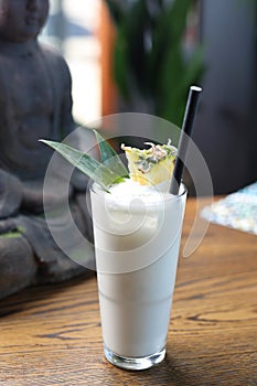 Pina colada drink. Cocktail based on rum, coconut milk and pineapple in a long glass, on a wooden background.