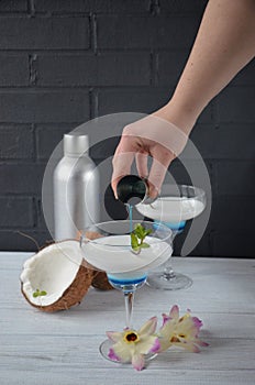 Pina colada drink in cocktail glass decorated with coconut and orchid flowers