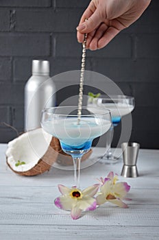 Pina colada drink in cocktail glass decorated with coconut and orchid flowers