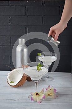 Pina colada drink in cocktail glass decorated with coconut and orchid flowers