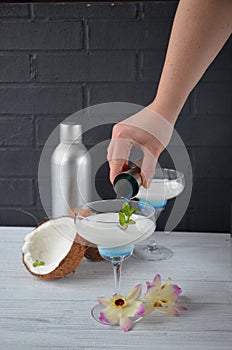 Pina colada drink in cocktail glass decorated with coconut and orchid flowers