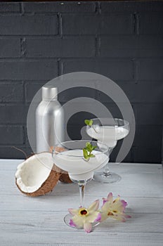 Pina colada drink in cocktail glass decorated with coconut and orchid flowers