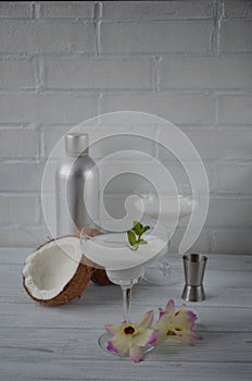 Pina colada drink in cocktail glass decorated with coconut and orchid flowers