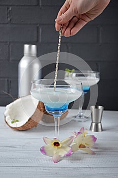 Pina colada drink in cocktail glass decorated with coconut and orchid flowers