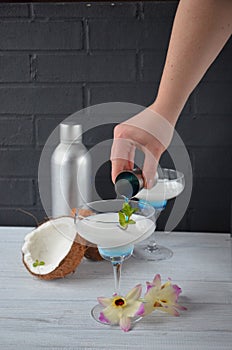 Pina colada drink in cocktail glass decorated with coconut and orchid flowers