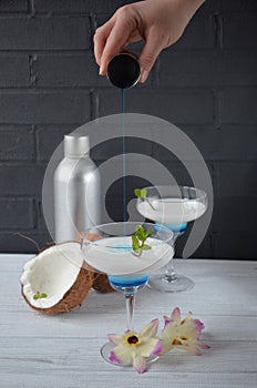 Pina colada drink in cocktail glass decorated with coconut and orchid flowers