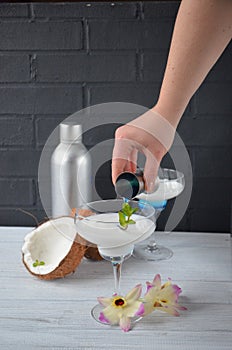 Pina colada drink in cocktail glass decorated with coconut and orchid flowers