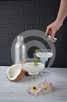 Pina colada drink in cocktail glass decorated with coconut and orhid flowers