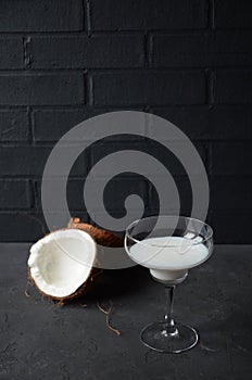 Pina colada drink in cocktail glass decorated with coconut and orhid flowers