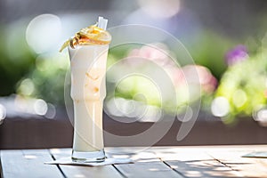 Pinacolada cocktail with straws and orange on top served in a high glass on a summer terrace