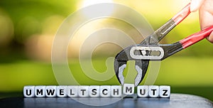 A pincer takes a dice and changes the German word `Umweltschmutz` pollution of environment to `Umweltschutz` protection of eco