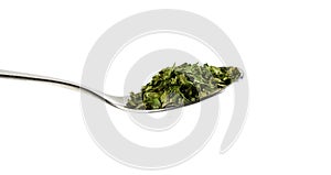 Pinch of dried parsley on teaspoon isolated on white background