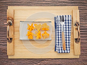 Pinched Gold Egg Yolks or Khanom Thong Yip on a plate over a wooden tray