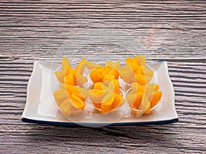 Pinched Gold Egg Yolks or Khanom Thong Yip in the Thai language are on a plate.