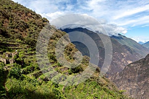 Pinchinuyok ancient Inca ruins surrounded by mountain peaks and clouds above the green canyon in Peru