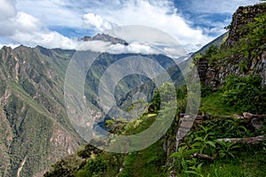 Pinchinuyok ancient Inca ruins surrounded by mountain peaks and clouds above the green canyon in Peru