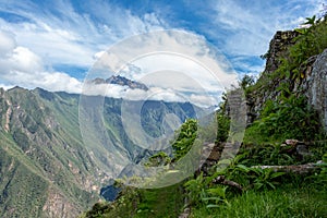 Pinchinuyok ancient Inca ruins surrounded by mountain peaks and clouds above the green canyon in Peru photo
