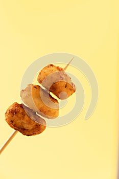 Pincho of home-made croquettes of ham, typical Spanish dish on yellow background