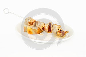 Skewer of meat on a slice of bread and on top of a white plate. photo