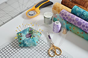 Pincushion, craft mat, scissors, rotary cutter, fabric rolls, sewing and quilting accessories