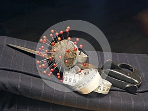 Pincushion, an old scissors and a measuring tape on gray flanel fabric